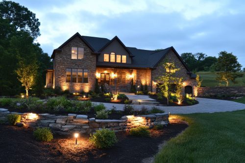 Contractors installing outdoor lighting fixtures for enhanced nighttime visibility and aesthetic appeal in residential spaces