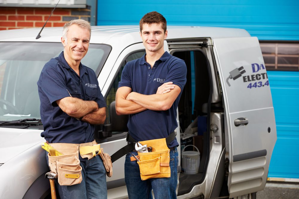 Workers In Family Business Standing Next To Van